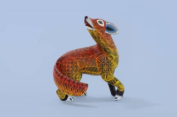 A medium coyote tona or alebrije, painted in orange and yellow gradient with black ink details on the top layer